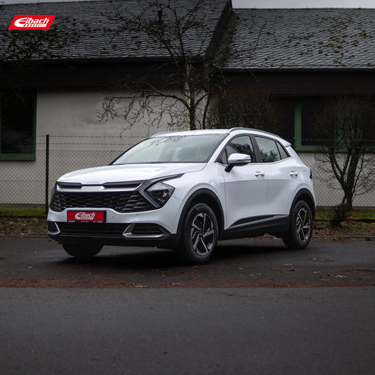 Ein weißer SUV parkt auf einer Straße vor einem Gebäude mit grün getönten Fenstern und einem dunkelgrauen Dach. In der oberen linken Ecke des Bildes ist das Eibach-Logo zu sehen. Ein weißer SUV parkt auf einer Straße vor einem Gebäude mit grün getönten Fenstern und einem dunkelgrauen Dach. In der oberen linken Ecke des Bildes ist das Eibach-Logo zu sehen.