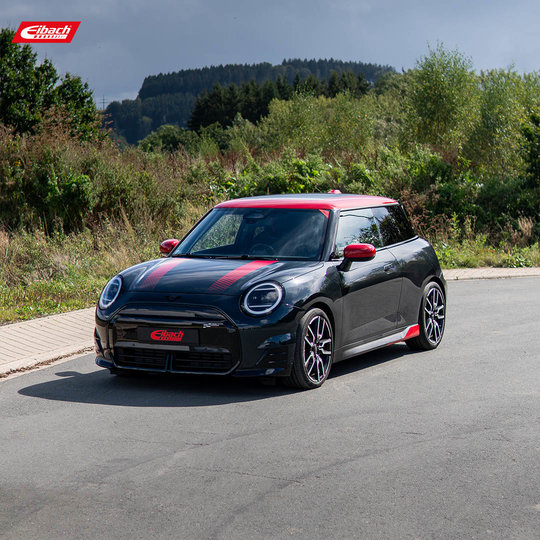 A black Mini Cooper with red accents is parked on a paved road, surrounded by greenery and trees, under a cloudy sky. The car features sporty design details and alloy wheels. A black Mini Cooper with red accents is parked on a paved road, surrounded by greenery and trees, under a cloudy sky. The car features sporty design details and alloy wheels.