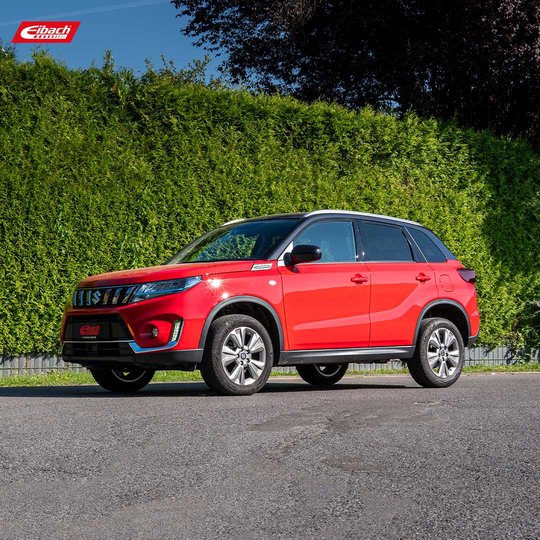 A red SUV is parked on a paved surface in front of a tall green hedge, under a clear sky. The car has sporty details and alloy wheels. The Eibach logo appears in the top left corner. A red SUV is parked on a paved surface in front of a tall green hedge, under a clear sky. The car has sporty details and alloy wheels. The Eibach logo appears in the top left corner.