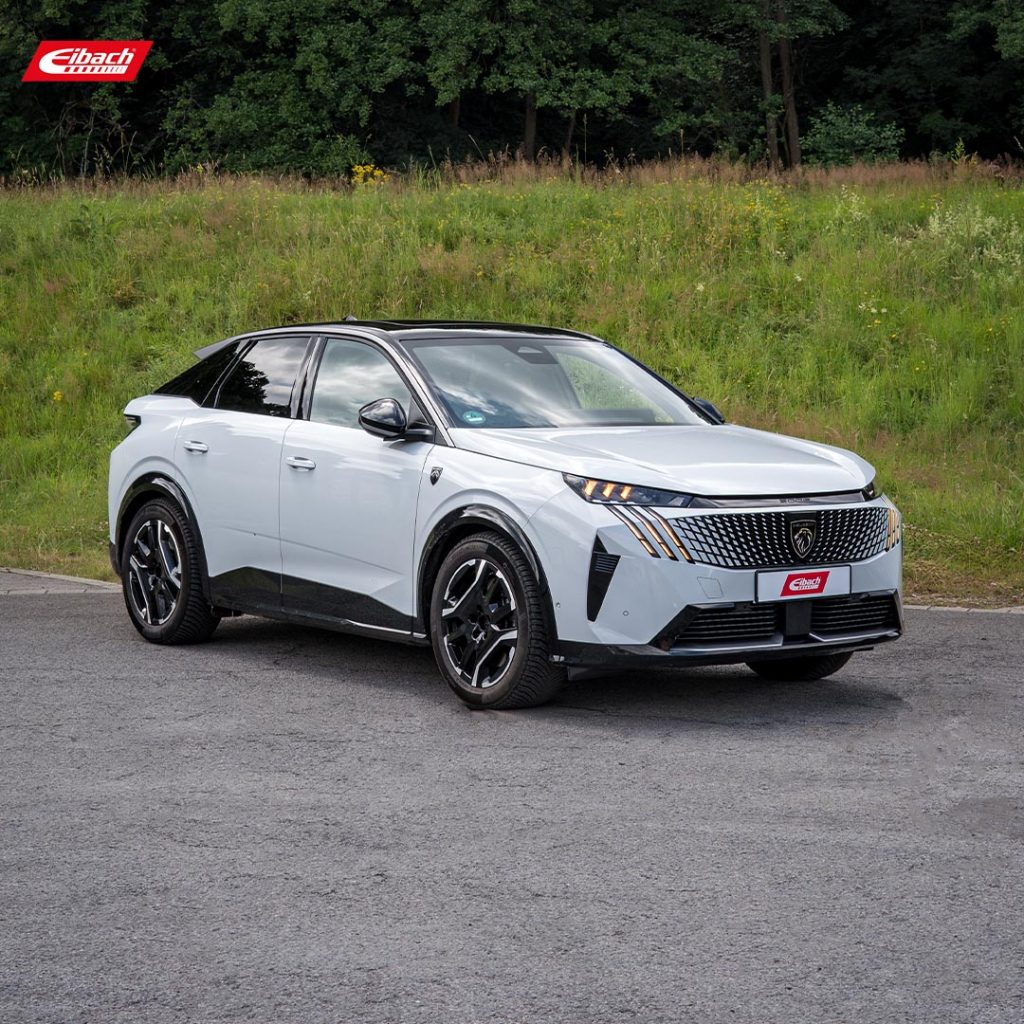 Ein weißer Peugeot 3008 SUV mit schwarzen Akzenten ist auf einer gepflasterten Fläche in der Nähe einer Wiese und von Bäumen geparkt. Auf dem vorderen Nummernschild und in der linken oberen Ecke des Bildes befindet sich der Schriftzug Eibach pro kit tieferlegung.