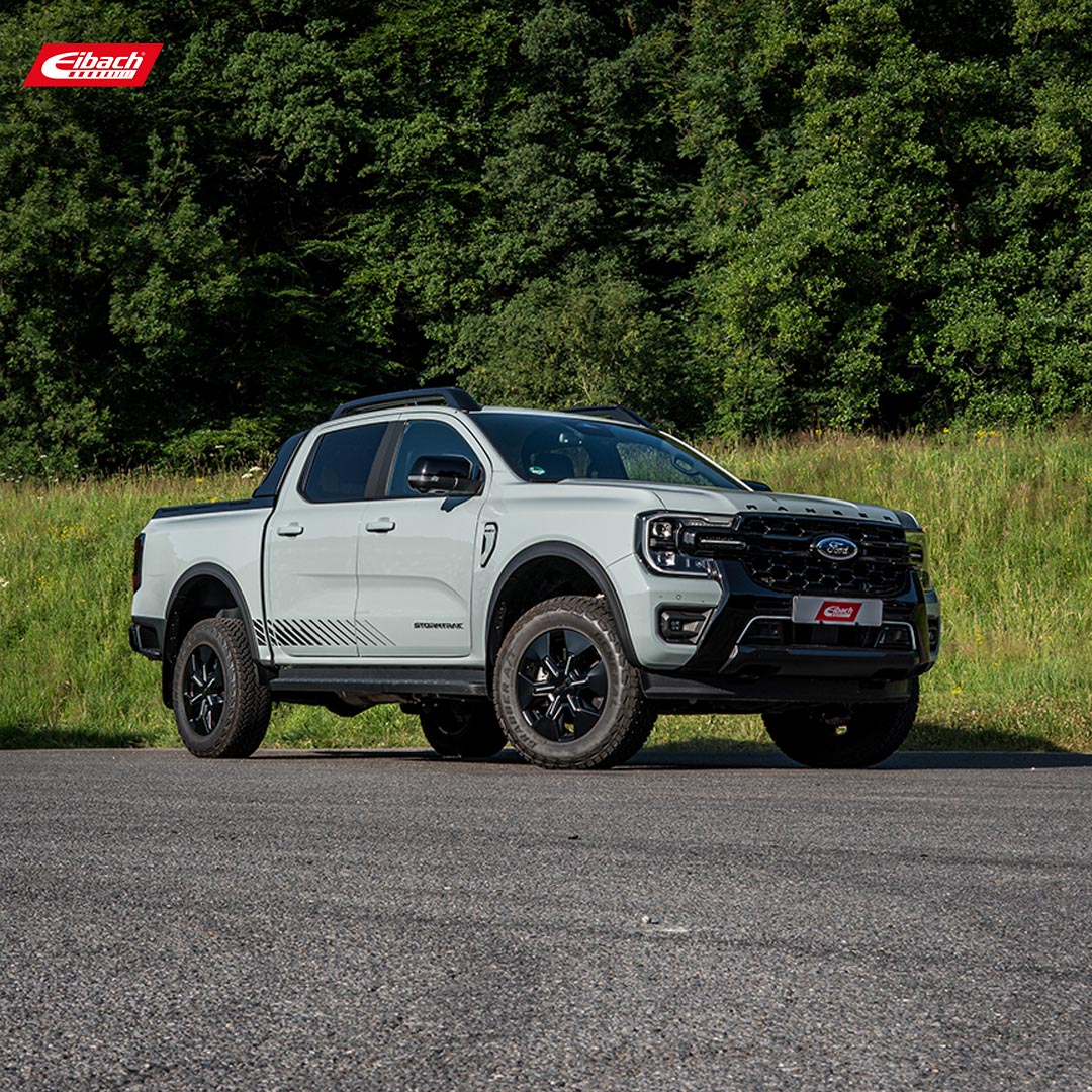 A light gray Ford Ranger 2.0 EcoBlue 4x4 pickup with black accents is parked on a paved area, with green trees in the background. The Eibach logo in the upper left corner highlights the test setup for this impressive truck model.
